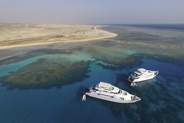 Aerial view of a marina in Port Ghalib, Egypt, with liveaboard boats ready for departure and crystal-clear Red Sea waters.
